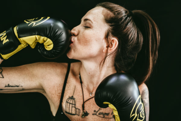 MUJER CON GUANTES DE BOXEO GOLPEANDOSE ELLA MISMA